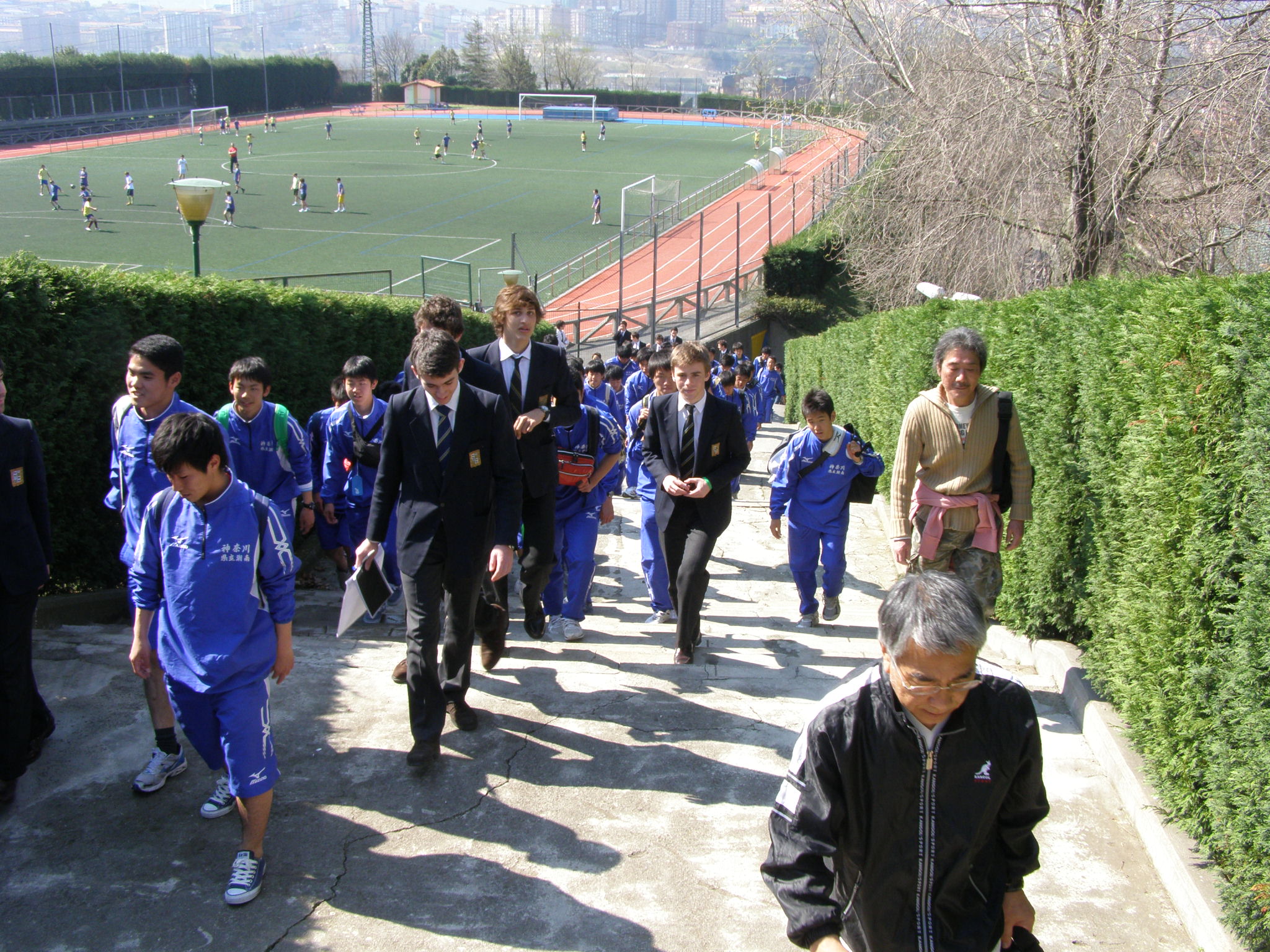 日本とスペインの学校交流、サッカー場の脇を選手たちが歩いている